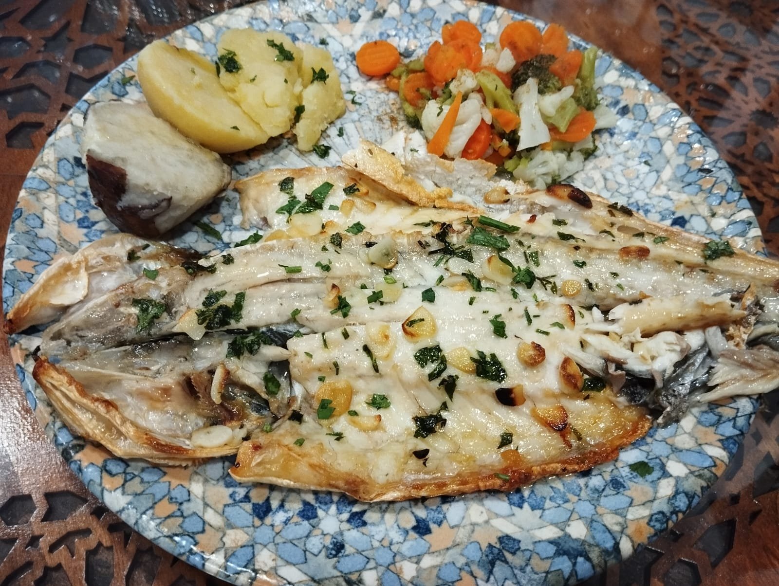 Butterflied fish with garlic and parsley, potatoes and vegetables