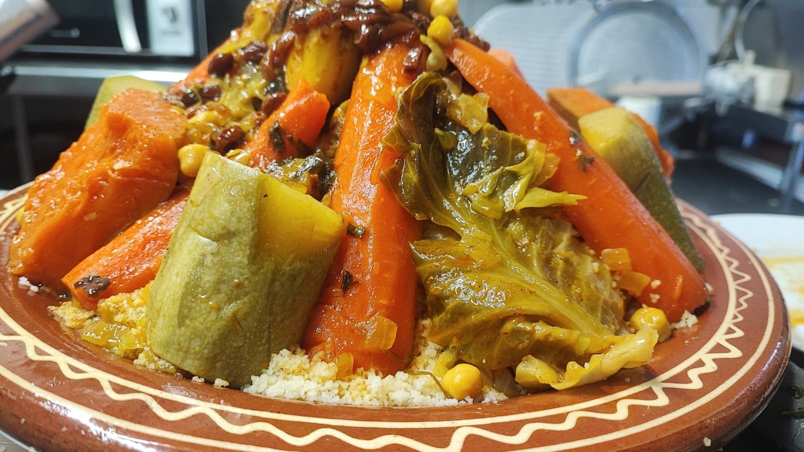 Couscous piled high with carrots, zucchini, cabbage and chickpeas in a hand-painted clay dish