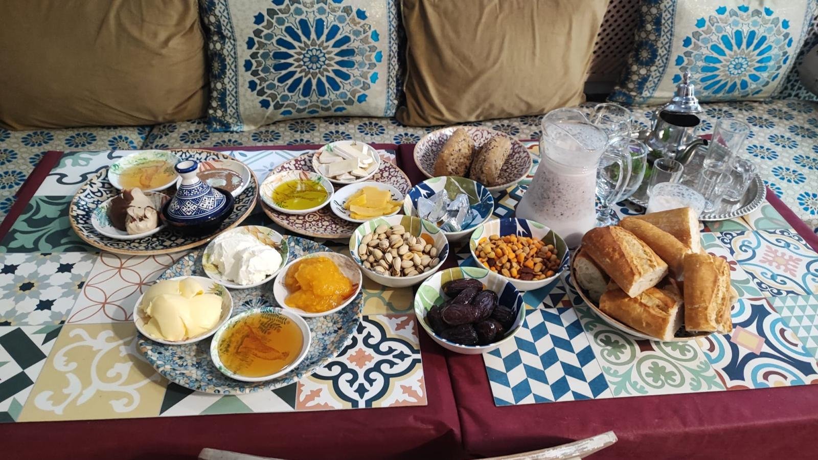 Silver Moroccan teapot and tea glasses beside bread, dates, nuts and honey