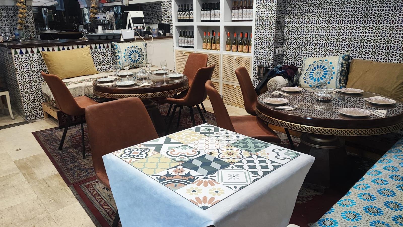 Dining room with round tables, patterned cushions and blue zellige tiles on the wall