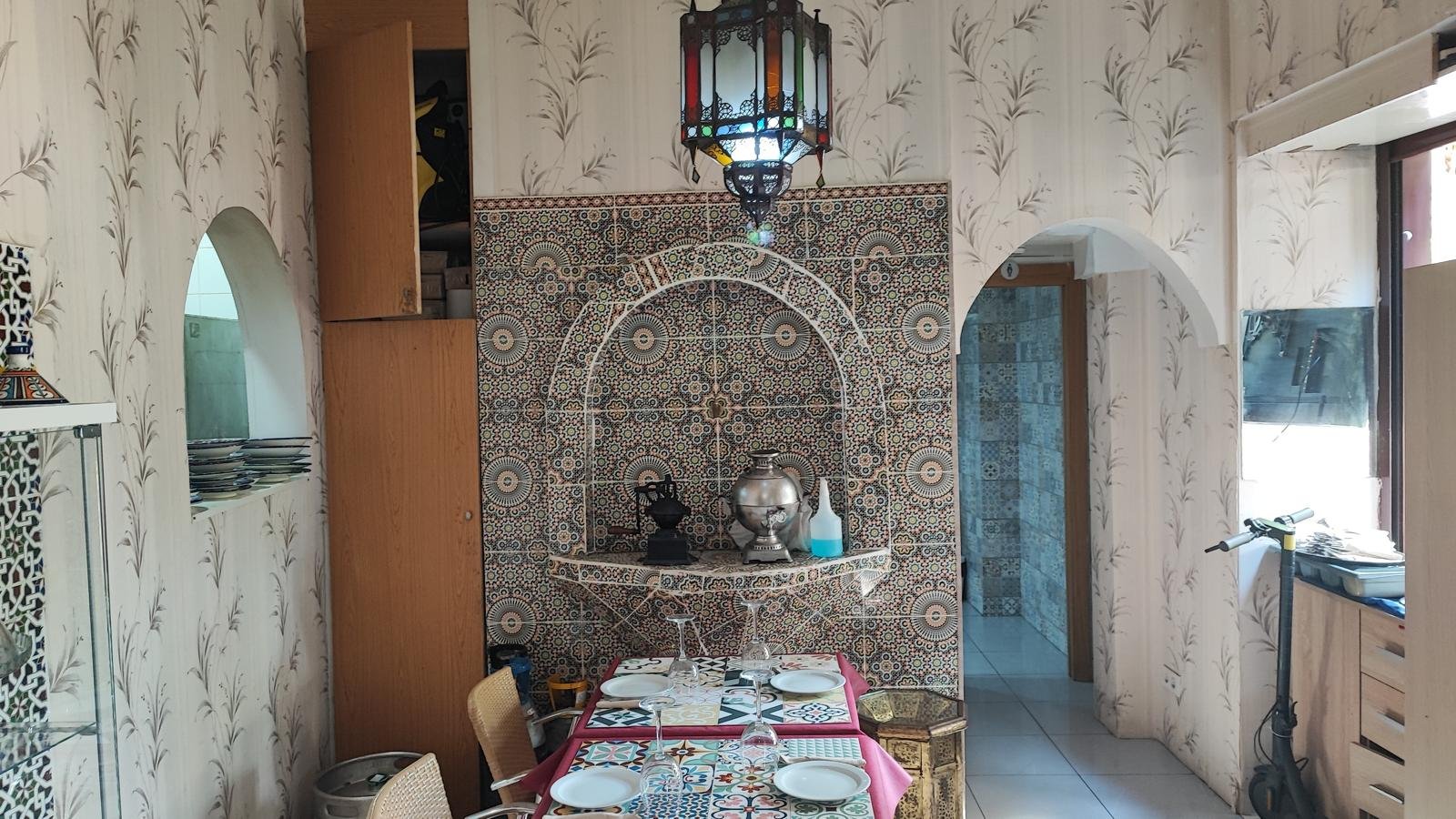 Indoor table beside a tiled wall fountain and a Moroccan lantern
